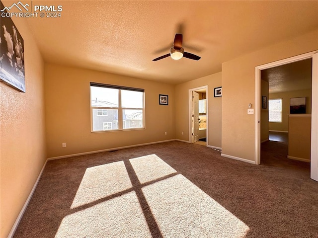 unfurnished bedroom with ceiling fan, dark carpet, and a textured ceiling