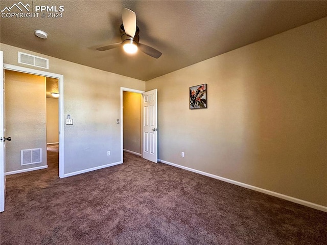 unfurnished bedroom featuring ceiling fan, a textured ceiling, and dark colored carpet