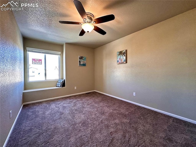 empty room featuring dark colored carpet, ceiling fan, and a textured ceiling