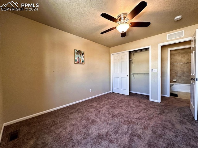 unfurnished bedroom featuring ceiling fan, a closet, a textured ceiling, and dark colored carpet