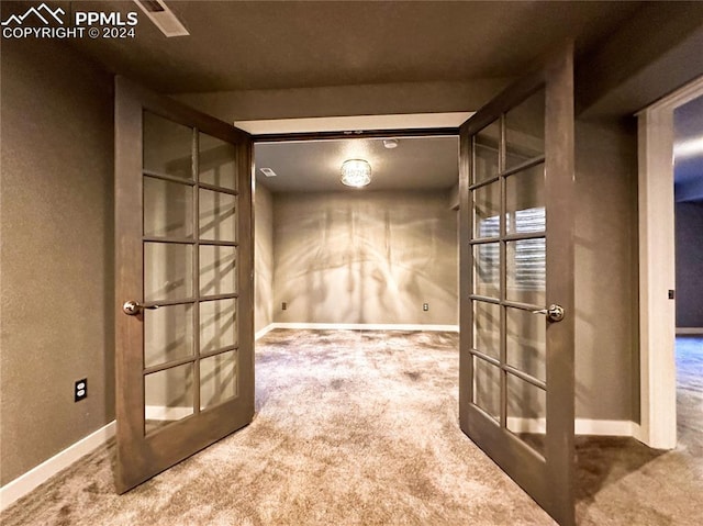 carpeted spare room featuring french doors