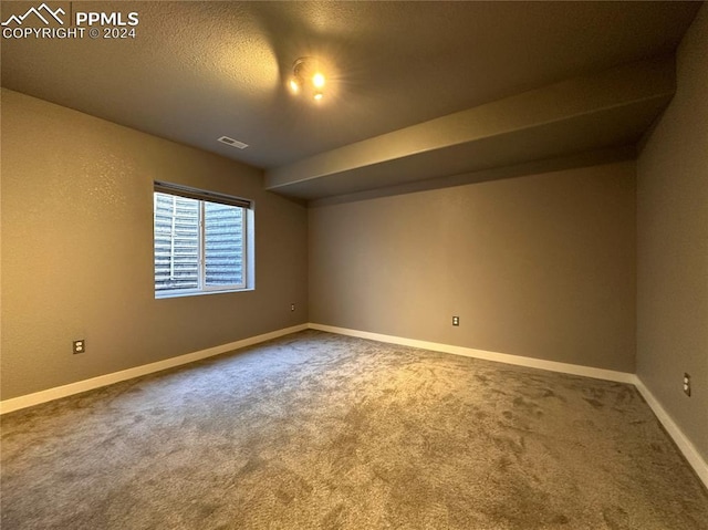 carpeted spare room featuring a textured ceiling, visible vents, and baseboards