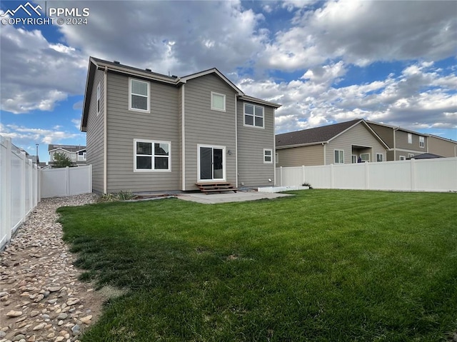 back of property featuring entry steps, a fenced backyard, a lawn, and a patio