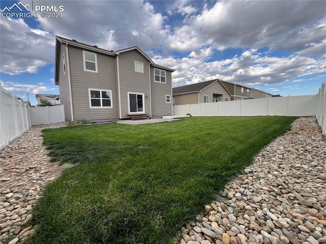 rear view of property with entry steps, a fenced backyard, a patio, and a yard