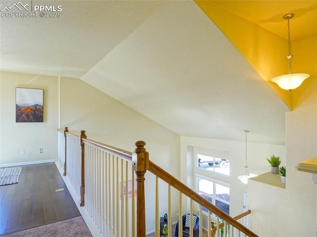 corridor with baseboards, vaulted ceiling, wood finished floors, and an upstairs landing