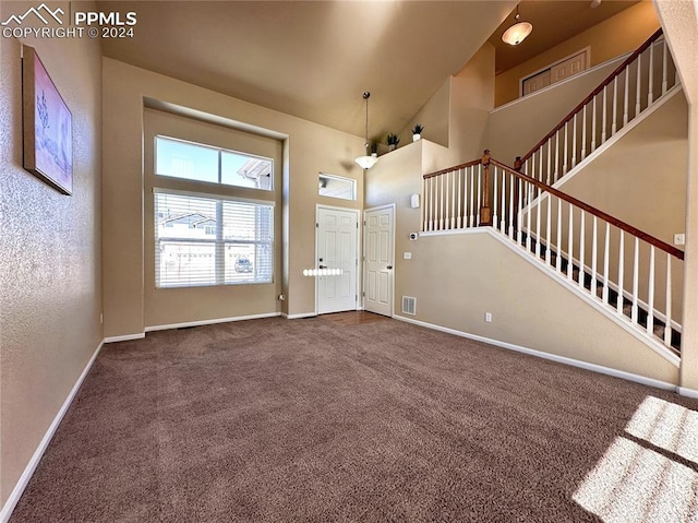 entrance foyer featuring a high ceiling, visible vents, baseboards, stairway, and carpet