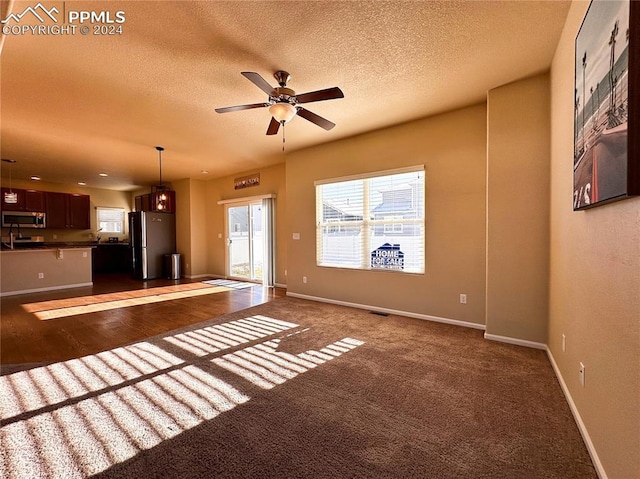 unfurnished living room featuring a textured ceiling, visible vents, a ceiling fan, and baseboards