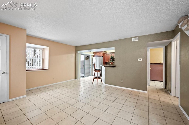 unfurnished room featuring light tile patterned floors and a textured ceiling