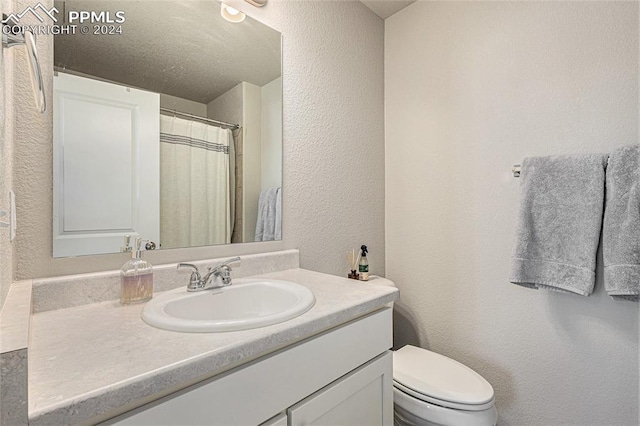 bathroom with vanity, toilet, and a textured ceiling