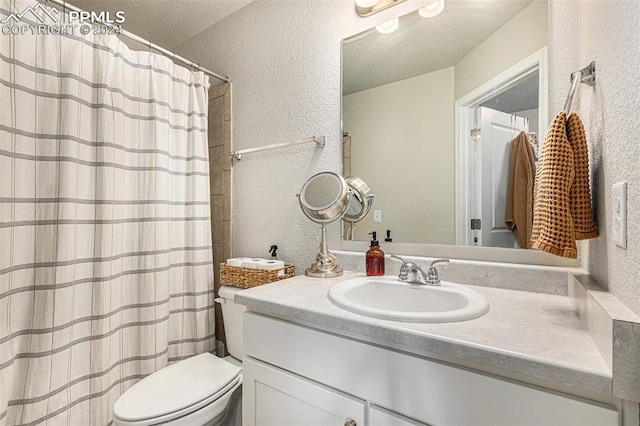 bathroom with vanity, toilet, and a textured ceiling