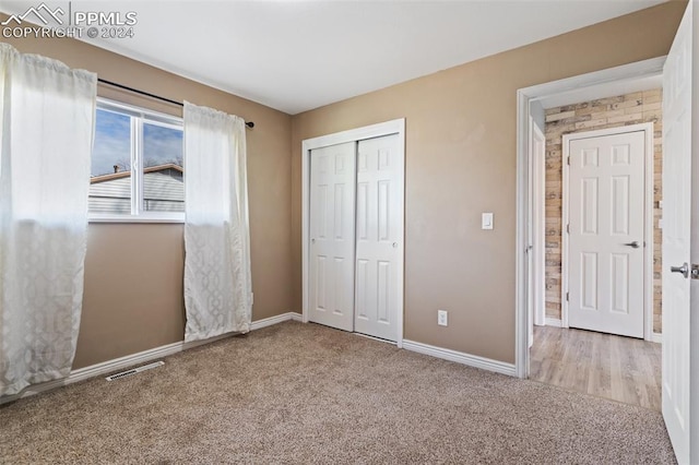 unfurnished bedroom featuring light colored carpet and a closet