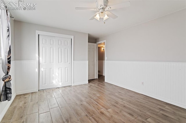 unfurnished bedroom with ceiling fan, light hardwood / wood-style flooring, and a closet