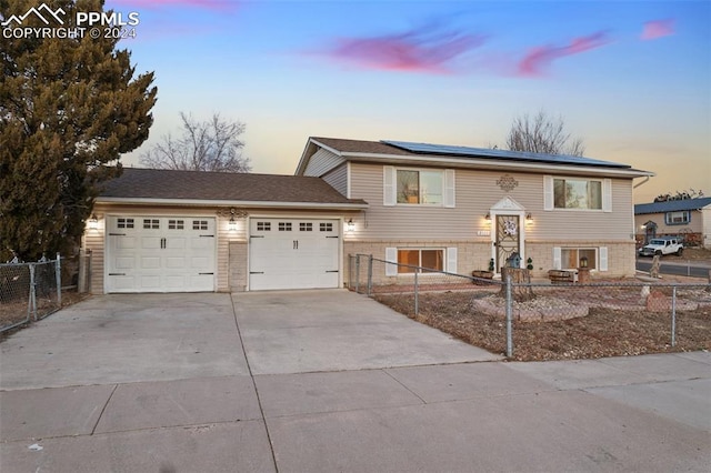 bi-level home featuring solar panels and a garage