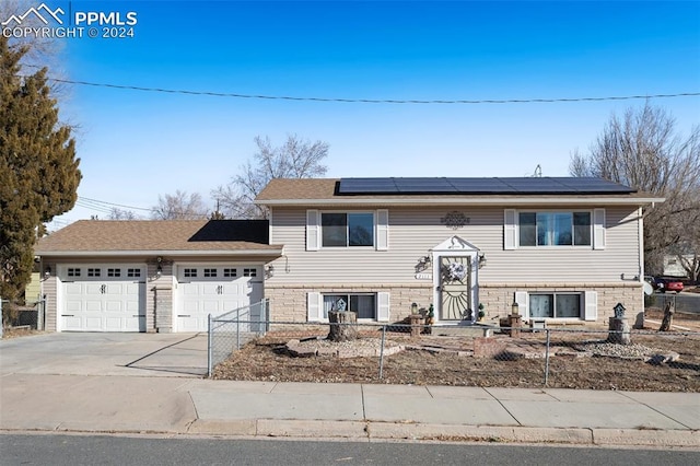 raised ranch with solar panels and a garage