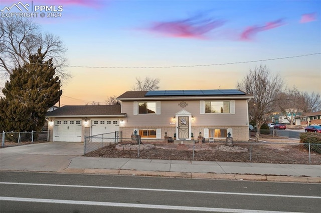 raised ranch with solar panels and a garage