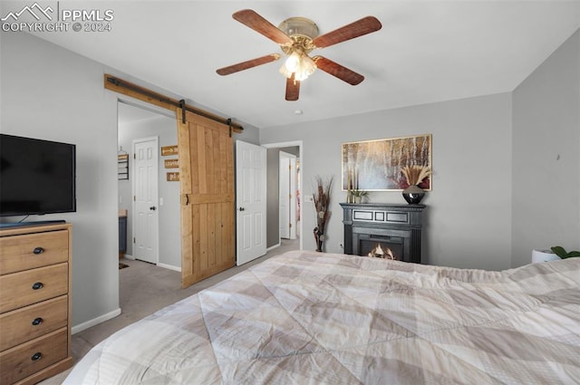 carpeted bedroom with ceiling fan and a barn door