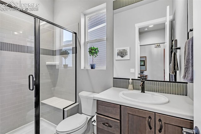 bathroom with a shower with door, toilet, and vanity