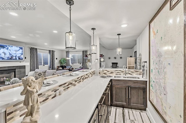 kitchen with decorative light fixtures, a tiled fireplace, and sink