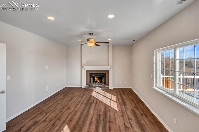 unfurnished living room featuring ceiling fan, dark wood-type flooring, and a brick fireplace