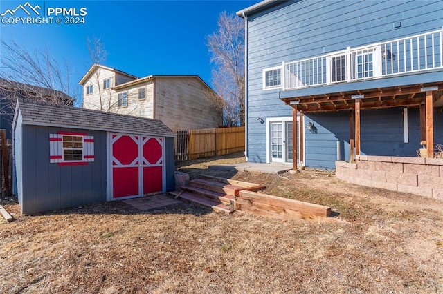 rear view of property featuring a wooden deck and a shed