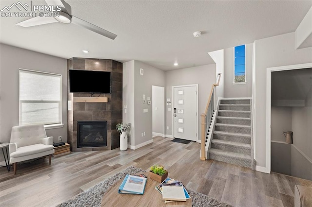 unfurnished living room with a fireplace, wood-type flooring, and ceiling fan