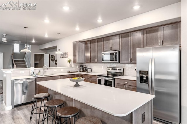 kitchen featuring kitchen peninsula, sink, appliances with stainless steel finishes, and a breakfast bar area