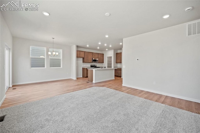 unfurnished living room featuring sink, a chandelier, and light wood-type flooring