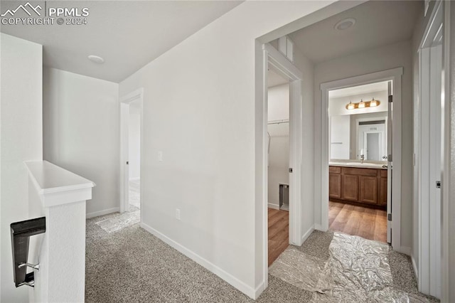 hallway with light colored carpet and sink