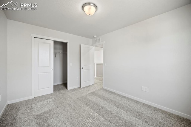 unfurnished bedroom with light carpet and a closet