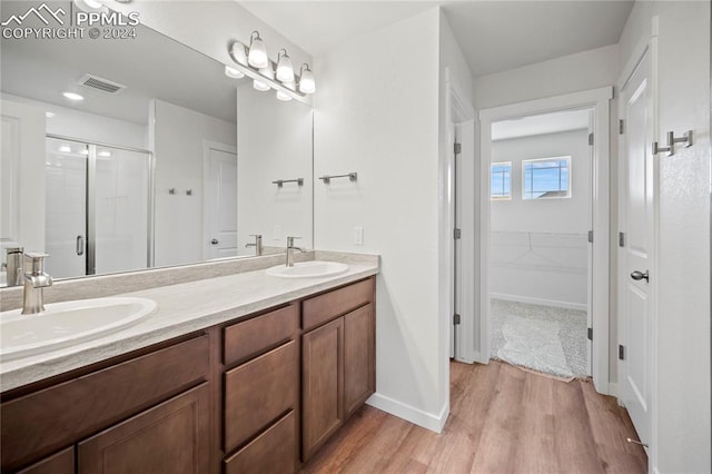 bathroom featuring hardwood / wood-style floors, vanity, and a shower with shower door