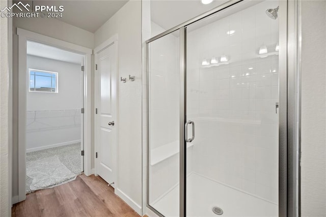 bathroom with wood-type flooring and an enclosed shower