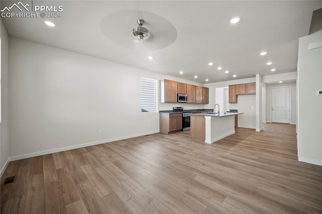 kitchen with ceiling fan, light hardwood / wood-style floors, a center island with sink, sink, and stainless steel appliances