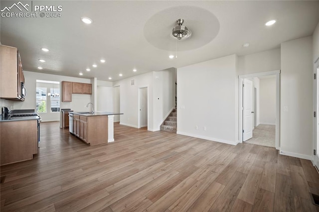 kitchen featuring ceiling fan, sink, light hardwood / wood-style floors, and an island with sink