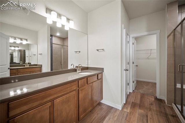 bathroom with hardwood / wood-style flooring, a shower with door, and vanity