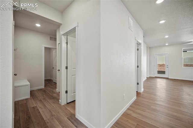 corridor featuring light hardwood / wood-style floors and a textured ceiling