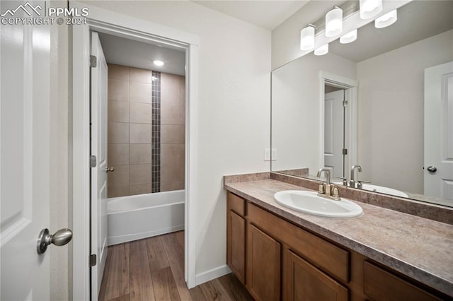 bathroom featuring tiled shower / bath combo, hardwood / wood-style flooring, and vanity