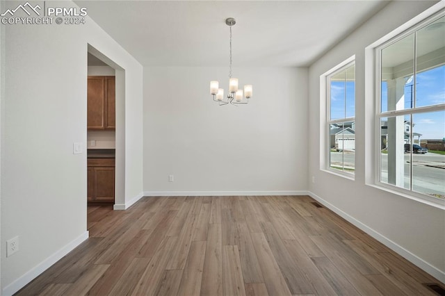 unfurnished room featuring wood-type flooring and a notable chandelier