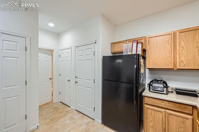 kitchen with black refrigerator and light brown cabinets