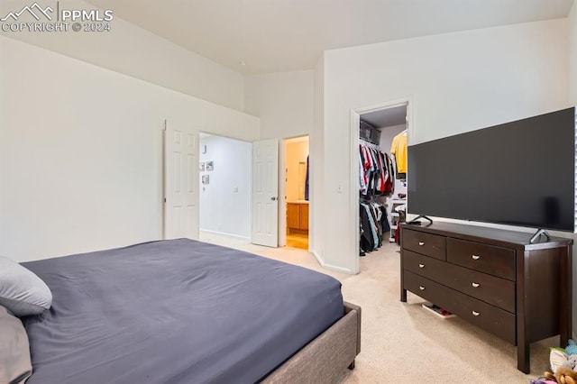 bedroom featuring a walk in closet, light colored carpet, ensuite bath, and a closet