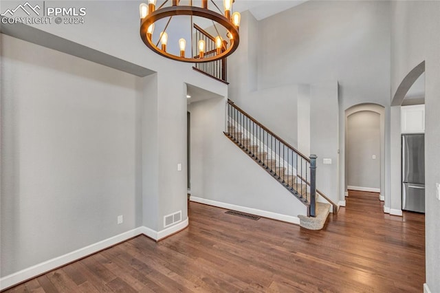 foyer featuring a towering ceiling, dark wood-type flooring, and an inviting chandelier