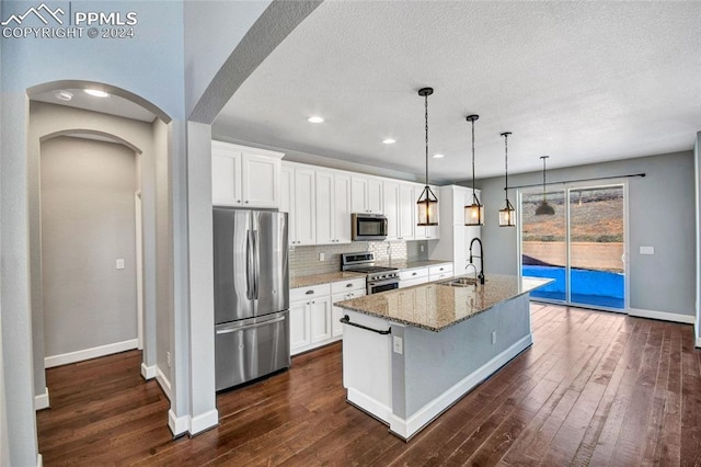 kitchen with white cabinetry, dark wood-type flooring, an island with sink, and stainless steel appliances