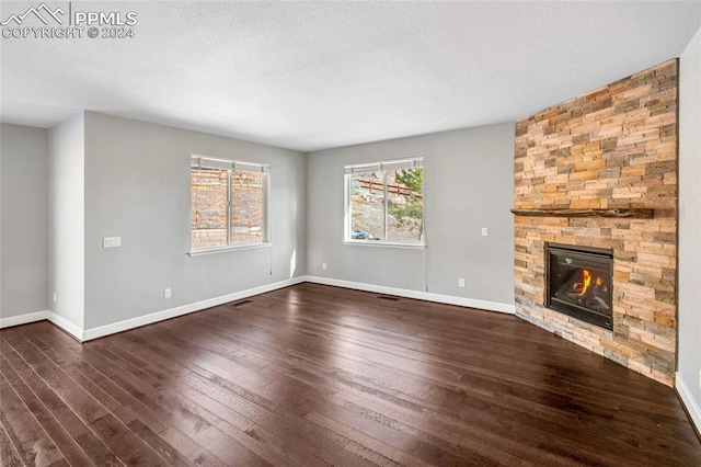 unfurnished living room with a textured ceiling, dark hardwood / wood-style flooring, and a fireplace