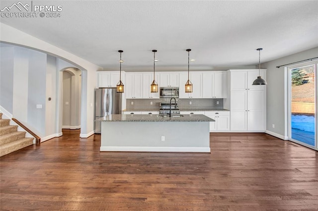 kitchen with dark hardwood / wood-style flooring, a kitchen island with sink, and appliances with stainless steel finishes