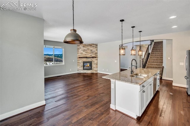 kitchen featuring sink, hanging light fixtures, an island with sink, dark hardwood / wood-style flooring, and white cabinetry