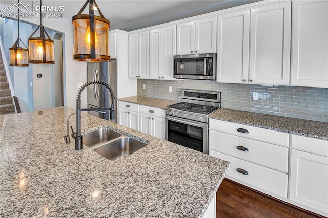 kitchen with white cabinets, pendant lighting, stainless steel appliances, and sink