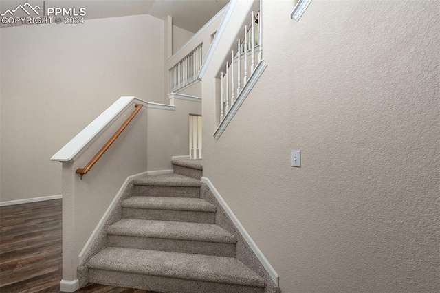 stairway featuring wood-type flooring and lofted ceiling