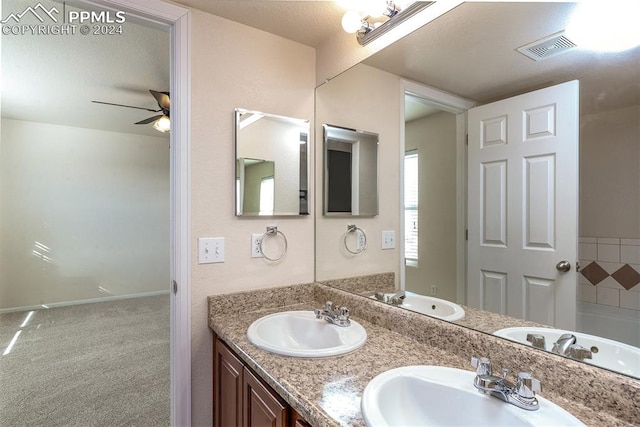 bathroom with ceiling fan, vanity, and a textured ceiling