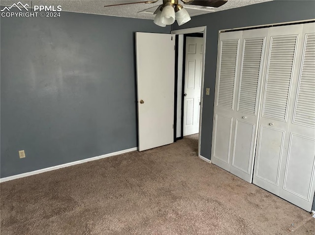 unfurnished bedroom featuring ceiling fan, a closet, light colored carpet, and a textured ceiling