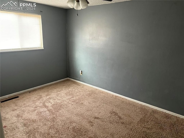 empty room with a textured ceiling, carpet floors, and ceiling fan