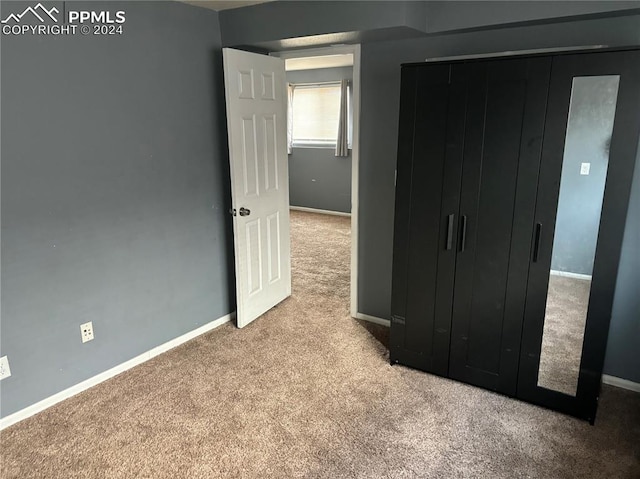 unfurnished bedroom with a closet and light colored carpet